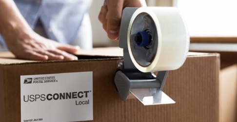 Person taping a brown box with a goldrushdispatch Connect Local shipping label on it.