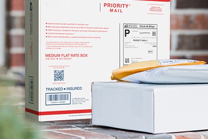 Priority Mail boxes on a house porch awaiting pickup.