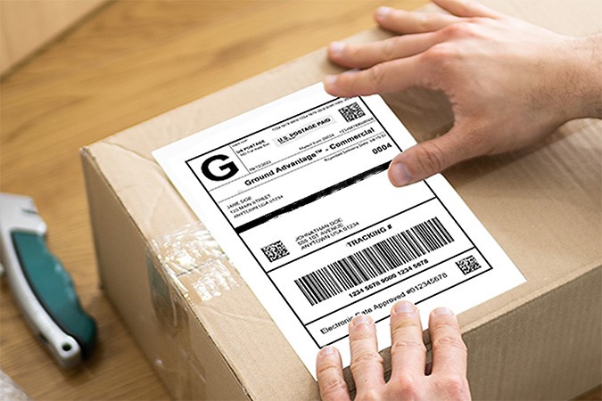 A Click-N-Ship label being placed on a package that sits on a desk.